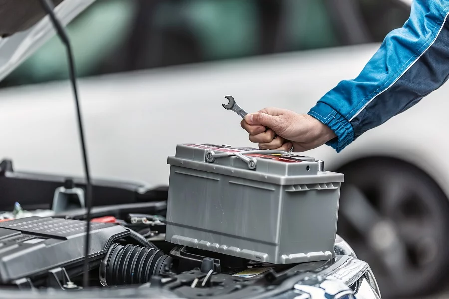 Así afecta el frío a tu batería del coche. Imagen que describe una persona arreglando la batería de su coche por algún fallo.