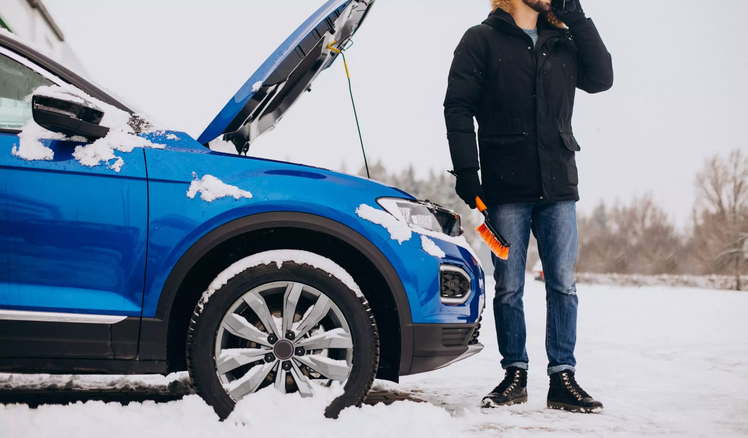 Batería del coche: ¿cómo le afecta el frío?. Imagen que describe a un hombre de pie junto al coche estropeado pidiendo ayuda.