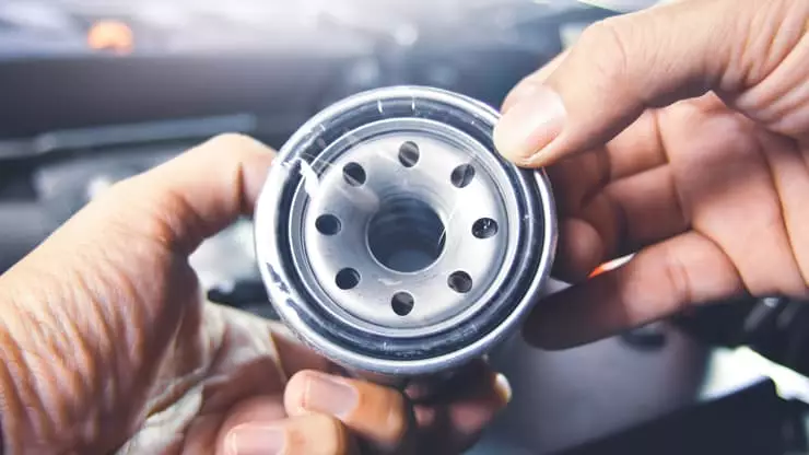 Filtro de aceite del coche: ¿cuáles son sus funciones?. Imagen que muestra un técnico manipulando el filtro de aceite de un vehículo.