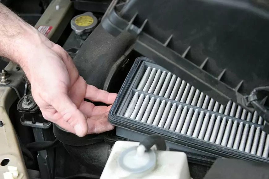 Todo lo que debes saber acerca del filtro de aire de tu coche. Imagen que muestra un técnico manipulando el filtro de aire del vehículo.