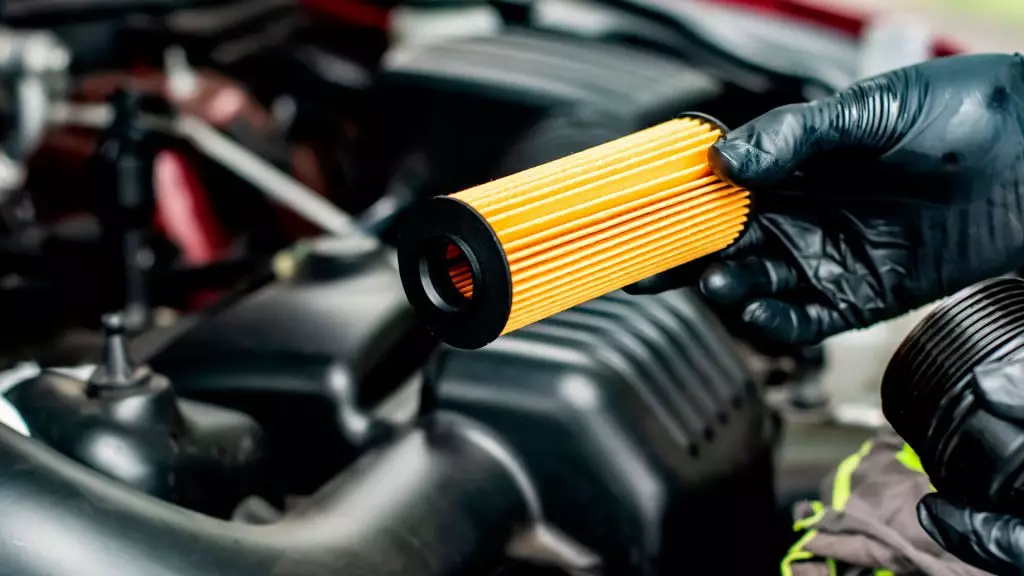 Filtro de aceite del coche: ¿cuáles son sus funciones?. Imagen que muestra a un técnico manipulando el filtro de aceite del coche.